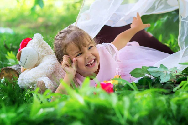 Het kleine meisje poseert buiten liggend in een TARVA en lacht — Stockfoto