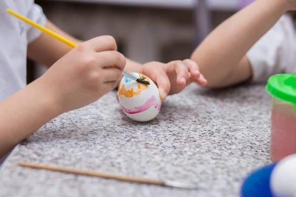 A criança pinta o ovo branco da Páscoa com pinturas a aquarela — Fotografia de Stock