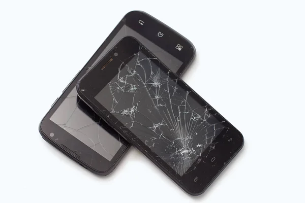 Dos teléfonos inteligentes negros rotos yacen el amigo en el amigo sobre un fondo blanco — Foto de Stock