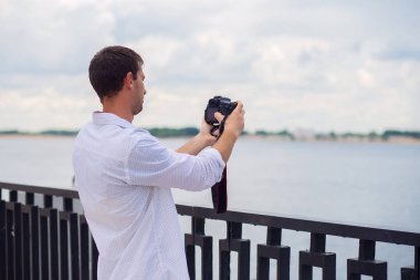 Beyaz gömlekli genç adam ayna daki setten nehri fotoğrafla.