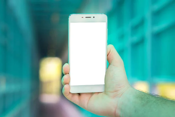 El gran teléfono inteligente blanco en una mano se cierra contra el fondo de un túnel. Espacio para el texto — Foto de Stock