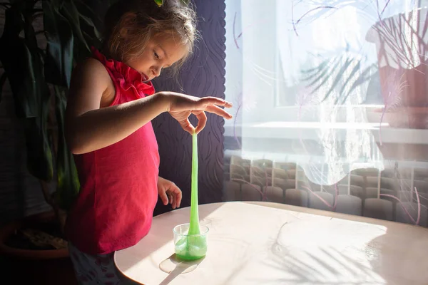The girl plays with an opposite toy - a green slime. The stretched slime — Stock Photo, Image
