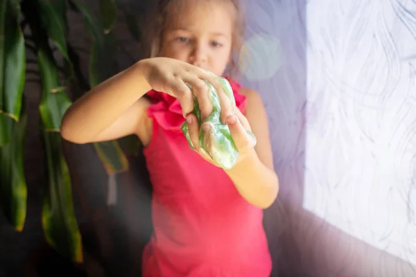 Ребенок играет с ирисками слизь зеленого цвета. Руки вверх. — стоковое фото