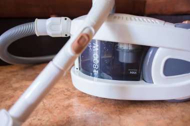 Kahverengi bir kanepe arka planına karşı bir katta dairede Aqua-filtre maliyetleri ile büyük beyaz elektrikli süpürge