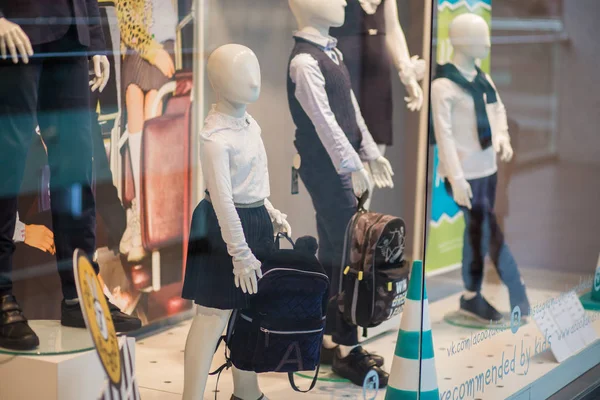 Çocuk okul üniforması ve sırt çantaları ile Aptallar büyük alışveriş merkezinde dükkanın bir show-window standı