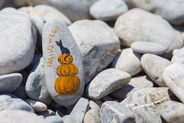 Pumpkin and black cat painted with watercolour on beach pebble