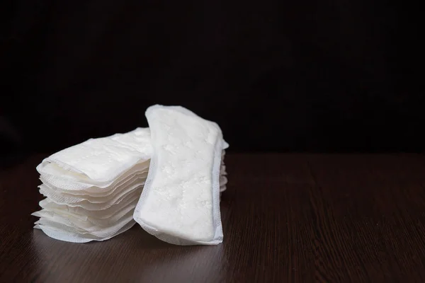 Women's white sanitary pads for every day are stacked on a black background — Stock Photo, Image
