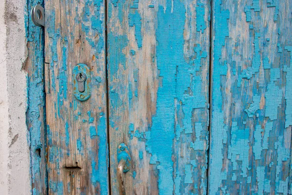 Parte de uma velha porta de madeira com tinta azul descascando e um buraco de fechadura — Fotografia de Stock