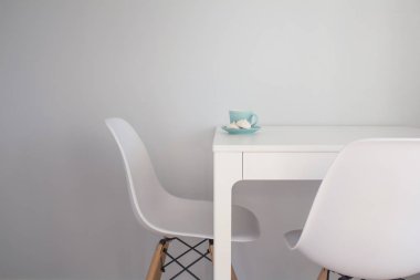 Turkuaz fincan çay ve beze beyaz sandalyeleri yakınındaki beyaz bir tablo