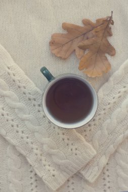 Sonbahar meşe yaprakları ve beyaz bir kazak üzerinde çay