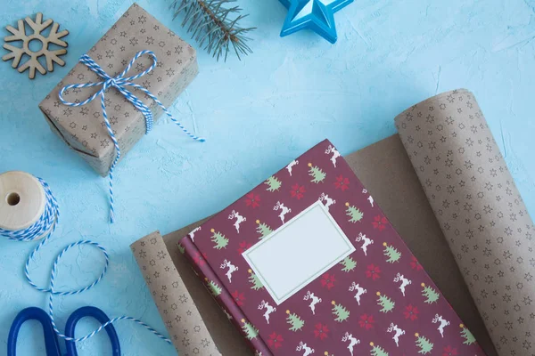 Packing of the Christmas book in gift paper on a blue background