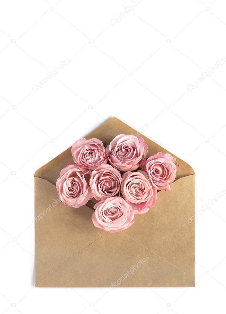 Pink roses in the craft paper envelope on the white background. Flower greeting card