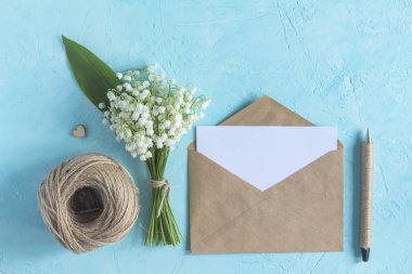 Lily vadi buketi ve mavi yüzeyüzerinde zanaat kağıt zarf. Üst görünüm bahar çiçek kartı