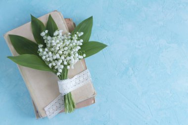 Lily vadi buketi eski bir kitap yığını üzerinde. Üst görünüm bahar çiçek kartı