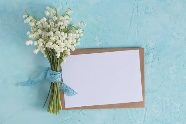 Lily of the valley bouquet on the blue surface. Top view spring flower card