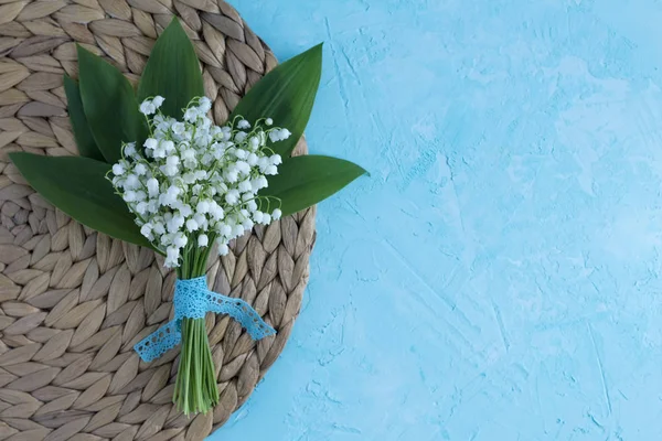 Lily of the valley bouquet on the blue surface. Top view spring flower card