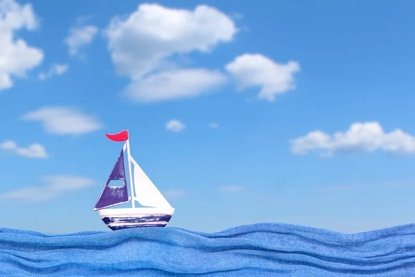 Toy iron ship on the fabric waves. Summer background