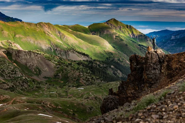 Genç kadın Backpacker zafer poz yukarı yükseltilmiş silah üstünde tepe-in dağ Colorado ABD ile yapılan