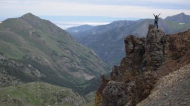 Kadın Backpacker kollarını yukarı dağın zirvesinde tırmandıktan sonra yükseltir 