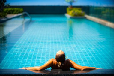 Young Woman relaxing by the side of the infinity pool 