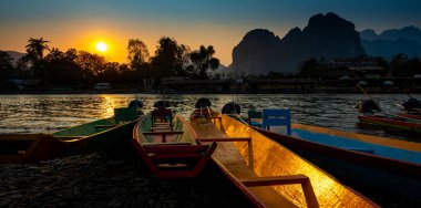 Sunset Nam Song nehrinde geleneksel Laos kanoları. Kireçtaşı K