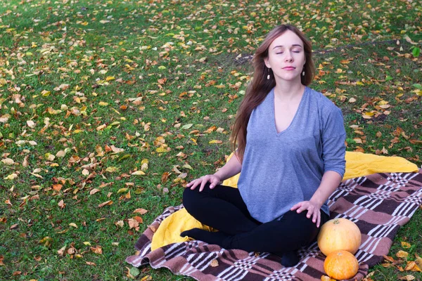 pregnant yoga woman with plaid and pumpkins portrait in autumn park on the grass, breathing, stretching, statics. outdoor, forest. concept of healthy lifestyle and relaxation. meditation.