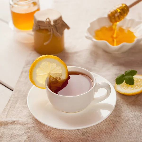 Cup of herbal tea, honey and lemon on wooden background