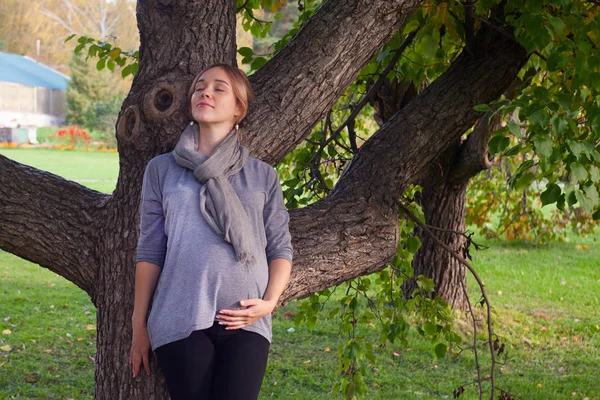 Female face, closed eyes close-up, A pregnant woman standing alone in the park, melancholy eyes closed