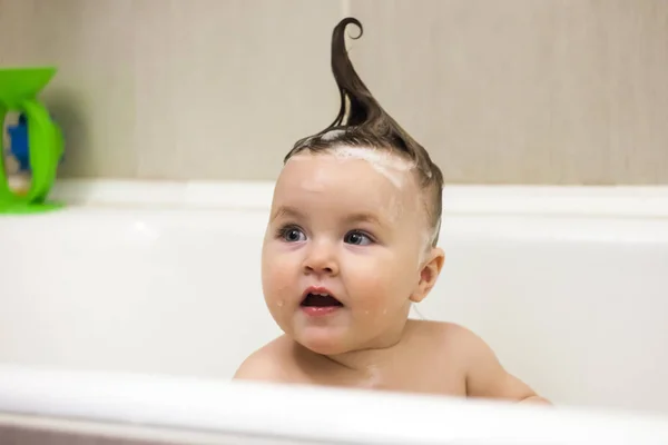 Funny baby sitting in the bathtub, playing and splashing. Bathroom time, washing time. It's good to be clean