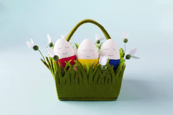 Funny easter eggs in a green basket, smiling faces