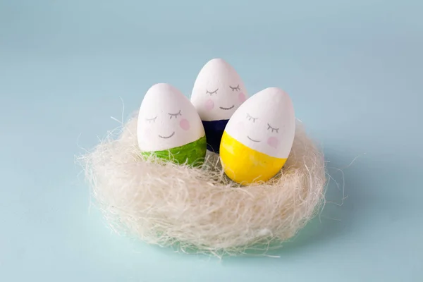 funny cute multi-colored eggs in the nest - easter background