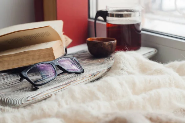 a cozy place to read on the windowsill - Asian tea, a warm scarf, a book, an atmosphere of coziness, inspiration, relaxation at home