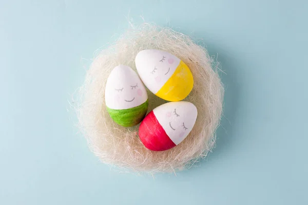 group of funny colorful eggs in the nest - a concept of merry Easter, funny characters, emotions