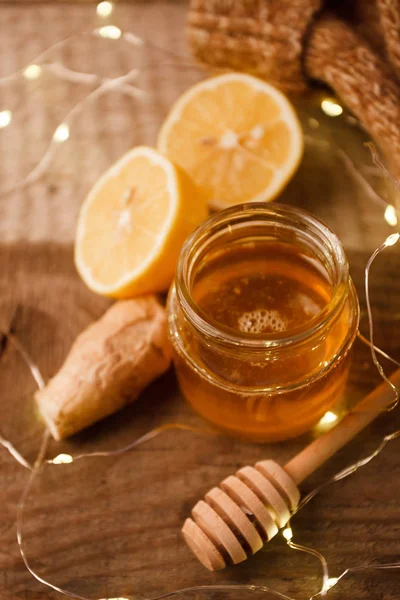 Composition with honey, lemon, ginger root as natural cold remedies on wooden background, winter holiday cozy home concept