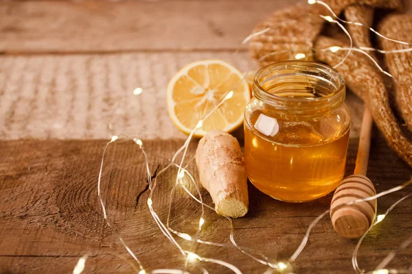 Composition with honey, lemon, ginger root as natural cold remedies on wooden background, winter holiday cozy home concept