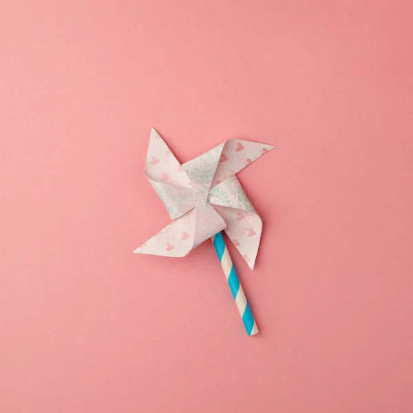 Paper windmill on pink background. minimal style