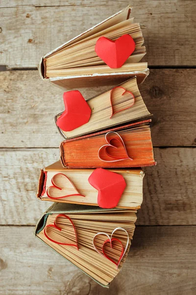 various old books and orogami papercraft red heart on vintage wooden background, concept of love knowledge, leisure time, university still life, valentines day background
