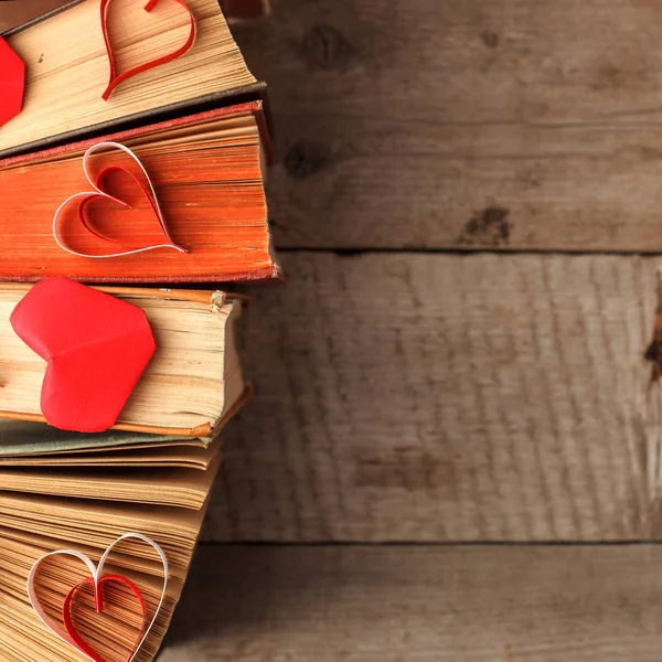 various old books and orogami papercraft red heart on vintage wooden background, concept of love knowledge, leisure time, university still life, valentines day background