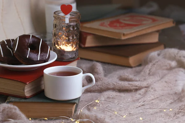 Mug with tea, books, donuts and woolen plaid winter blanket on v