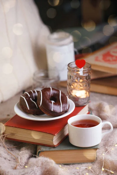 Mug with tea, books, donuts and woolen plaid winter blanket on v