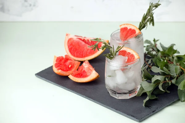 Refreshment grapefruit cocktail with rosemary on slate board. He