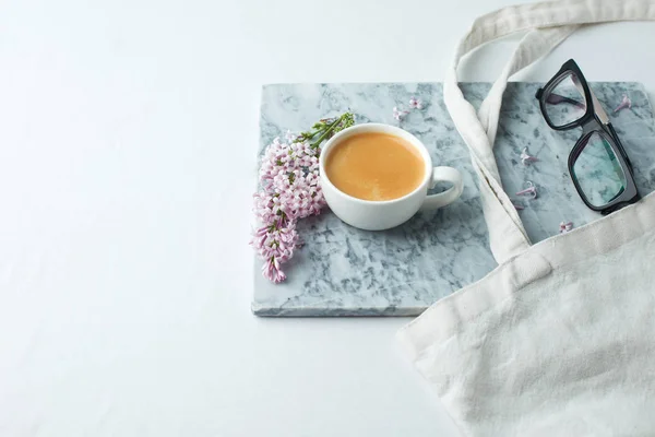 Minimalistic still life with coffee and lilac branches on marble