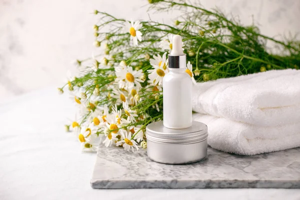 Chamomile flowers and cosmetic bottles of cream and serum essent