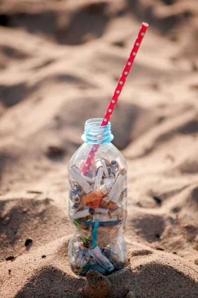Cocktail with garbage and straw on clean beach. Plastic ocean po