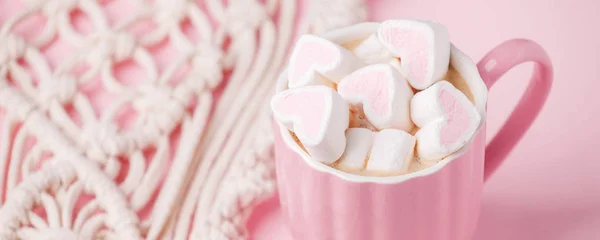 Cup of hot chocolate with pink heart shaped marshmallows and mac