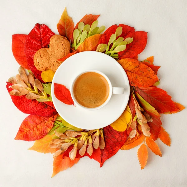 Cup of coffee and autumn leaves wreath on a white table, Seasona
