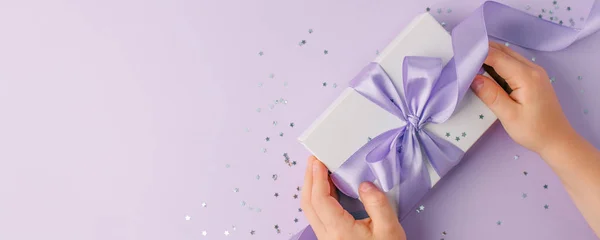 Gift box with lilac bow on violet background with delicate silve