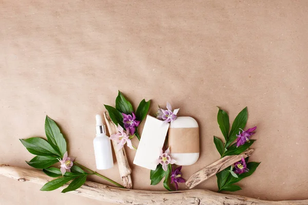 Herbal natural facial cosmetic products set with herbs and flowers on paper craft background, top view. Branding mock up, sustainable packaging, eco-friendly wellness products, self-care focus