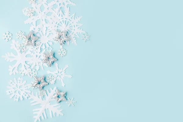 Winter pattern made of papercraft snowflakes on blue background. Winter concept. Flat lay. Tender concept of seasonal holiday, childrens creative activities, xmas, Christmas, New Year flyer