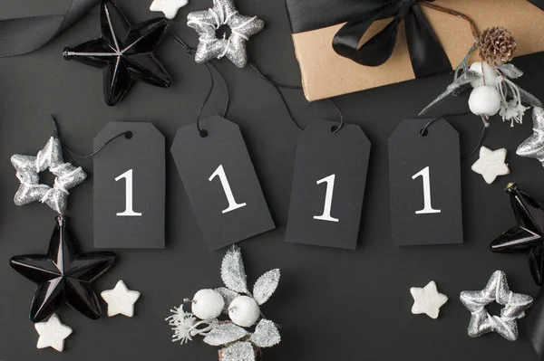 11 11 single day, 11 november seasonal sale - tags with copy space, gift box and decorations on black background. Monochrome stylish luxury concept, banner, voucher for shopping